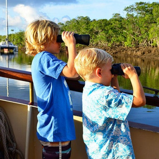 a young boy standing in front of a body of water